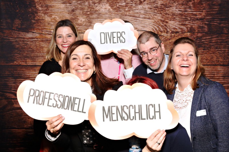 Teamfoto, fröhliche menschen, die Schilder mit den Werten "divers", "menschlich" und "professionell" hochhalten